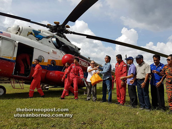 (From fourth left) Uggah and Dennis with villagers carrying the food aid from Bomba helicopter to be distributed to villagers of Long Loyang.