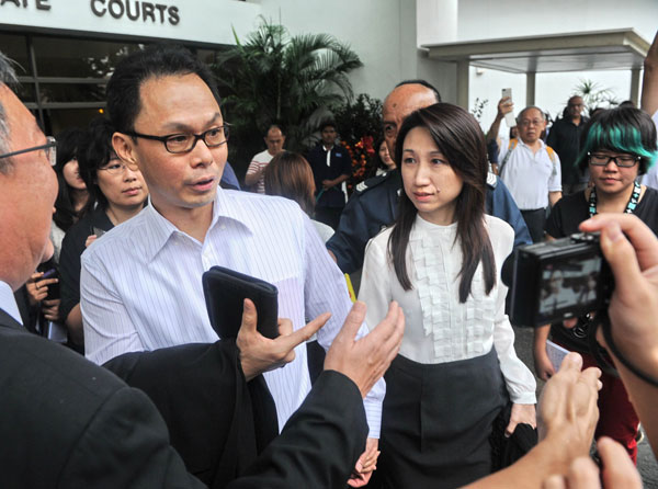 CLEARED OF CHARGES: Ng (centre left) and his wife leave after the hearing at the Subordinate court. — AFP photo