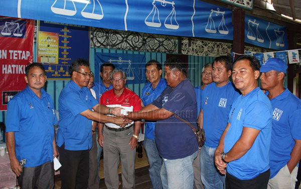 USE IT WELL: Nyabong (second left) hands over donation to a representative of fire victims of Uma Kulit whose 14-door longhouse was burnt last month as Ugak (fifth left) and others look on. 
