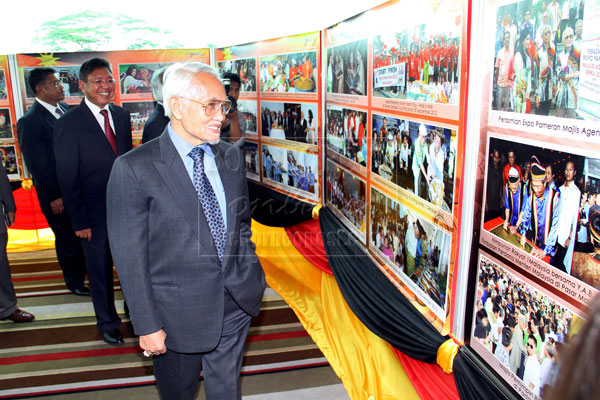 PROUD RECORD:  Taib viewing photographs on development exhibited in conjunction with the event yesterday. — Photo by Chimon Upon