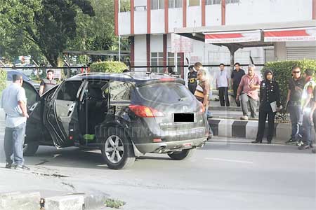 SIASAT: Anggota polis memeriksa kereta mangsa dalam kejadian tembakan di Miri, semalam.