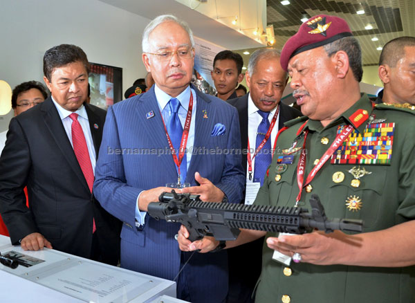 ASSAULT WEAPON:  Armed Forces chief Tan Sri Zulkifeli Mohd Zin (right) shows Najib a sub-compact SCW0921 rifle from the United States  after the launch of Lima 2013. At left is Defence Minister Datuk Seri Ahmad Zahid Hamidi.— Bernama photo