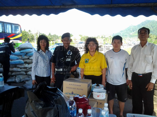 Chua (middle) with SAPP members after handing over food and drinks to security forces personnel on duty at Mile 5 Apas Road roadblock.