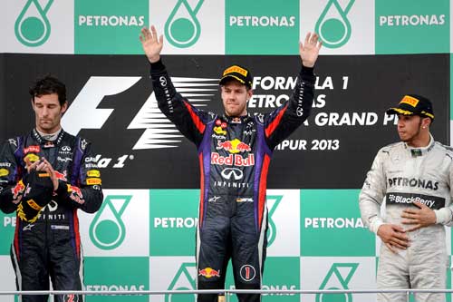 JUARA: Vettel (tengah) meraikan kemenangannya menjuarai Grand Prix Malaysia 2013 bersama Mark Webber (kiri) dan Lewis Hamilton pada sesi penyampaian trofi di Litar Sepang semalam. — Gambar AFP