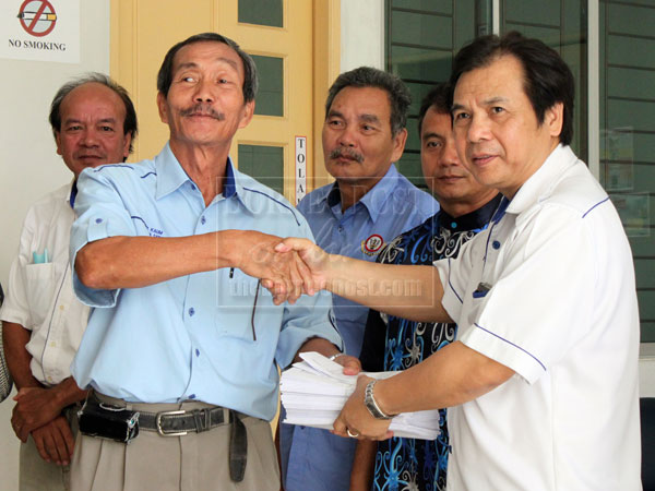 BN CARES: Dr Jerip (right) presenting the BR1M vouchers to one of the village chiefs.