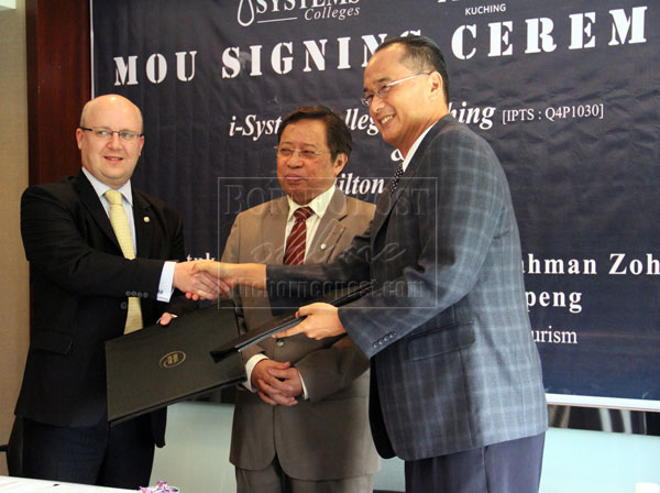 SMART PARTNERSHIP:  Warmington (left) and Tiong exchanging the MoU documents, witnessed by Abang Johari.