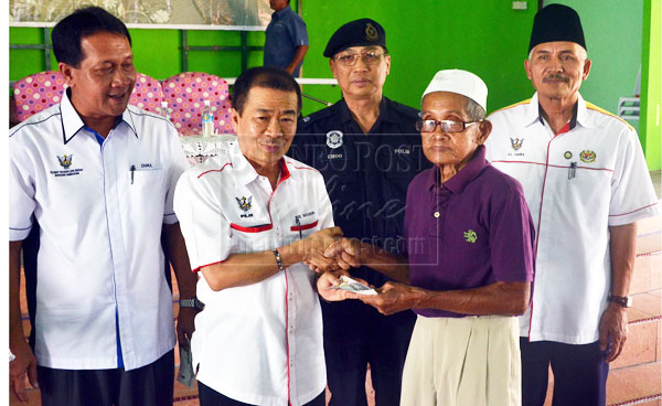 BN CARES: Naroden (second left) presents a BR1M 2.0 voucher to one of the recipients as others look on. 