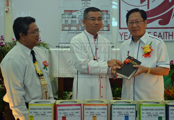 A TOKEN: Bishop Hii presents a memento to Lau (right).   