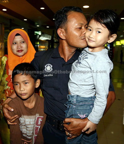 GLAD TO BE HOME: A Marine Operation Force personnel involved in operation in Lahad Datu, Sabah, Zakaria Ismail happily hugging his children Nurarisha Afreen Zakaria, Daniel Aiman Haikal Zakaria and  wife Muzdalifah Mohd as soon as he arrived at Sultan Ismail International Airport, Senai. — Bernama photo