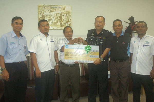 SINCERE CONTRIBUTION: Sondit hands over the donation to Mohd Bukhori. Razedy is at left. 