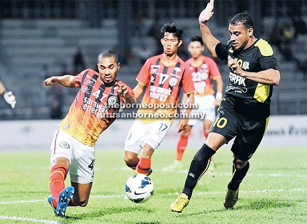 KAWAL: Pemain import Sarawak, Nyema Patrick Garhard (kiri) cuba mengawal bola daripada pemain import Perak, Charles Sauza Chad pada saingan Liga Super 2015 di Stadium Negeri Kuching malam kelmarin. — Gambar Bernama
