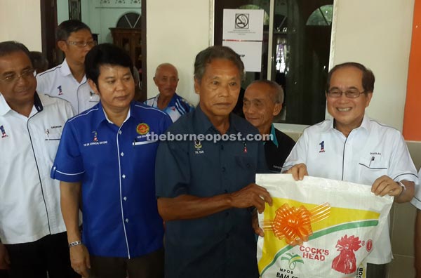 Uggah (right) presenting a bag of fertiliser from MPOB to one of the participants of the seminar. 