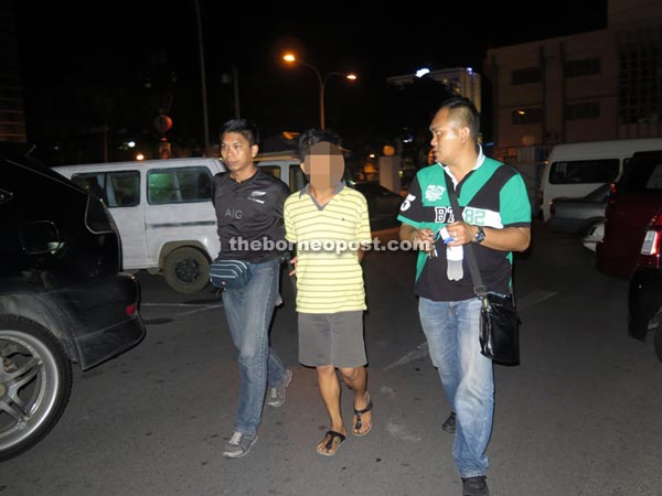 One of two suspects (centre) being taken to Miri Central Police Station.