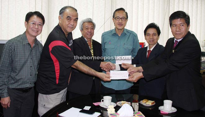 Chang (second from left), Koh  (third from left) and Ho (right) handing over the donation to Masidi.