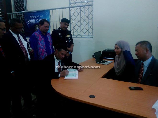 Zakaria signing the visitors' book during his visit to the Lahad Datu branch office of MACC at Jalan Hap Heng.