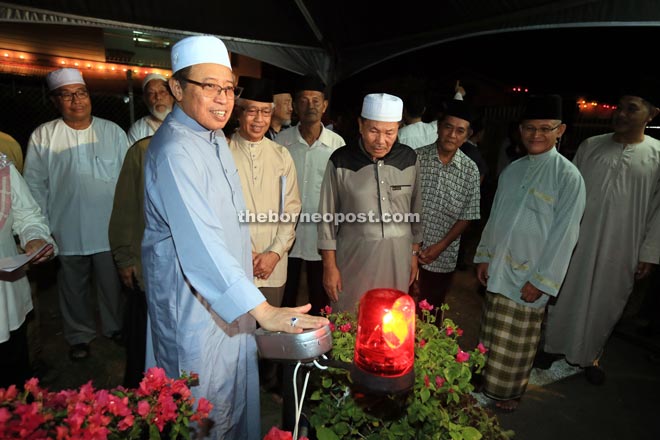 Abang Johari presses the button to launch the new LED streetlights for Kampung Satok. Also seen is Abdul Wahap (second left).