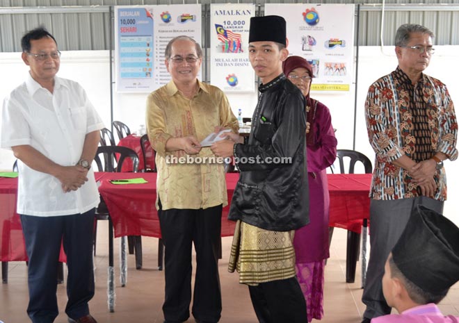 Uggah (second left) presents an education incentive to a recipient during the programme.