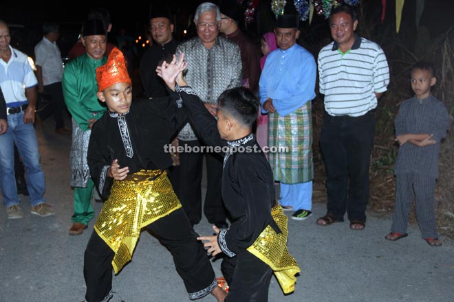 Manyin (second right) and others enjoy a ‘silat’ display performed by young exponents of the martial art at Kampung Tebakang Melayu. 