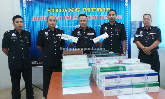 Douglas (centre) and his officers showing the seized contraband cigarettes. 