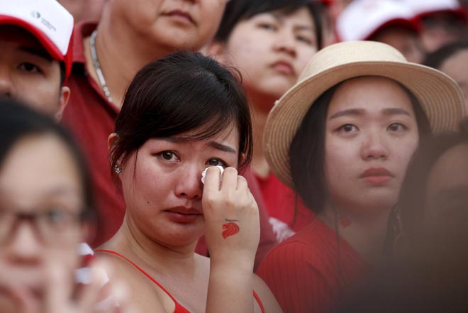 A woman cries as she watches a video tribute to the late former prime minister Lee Kuan Yew during Singapore’s Golden Jubilee parade at Padang near the central business district. — Reuters photo