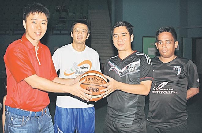 Larry (left)m handing over the basketball to deputy SDSC chairman Lionel Philip while organising chairman Jason Yeo (centre) and others look on.