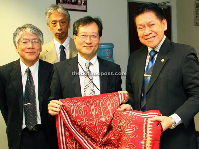 Kopli (right) presenting a piece of pua kumbu to Miyagawa as souvenir, as Nawata (left) and Murakami look on. — Photo by Chimon Upon