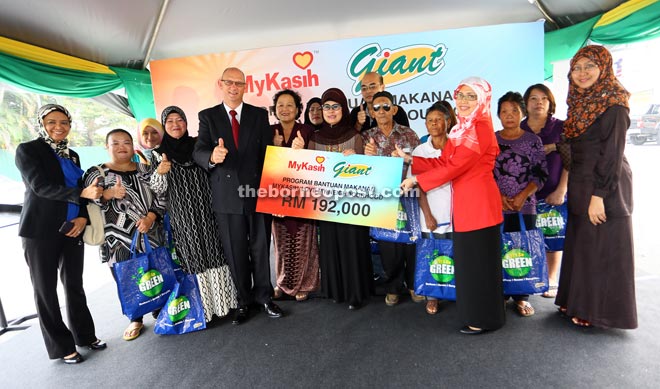 Fatimah (centre), together with Knight (fourth left) and Siti Khairon (third right) in a group photo with some of recipients of Giant-MyKasih food aid programme.
