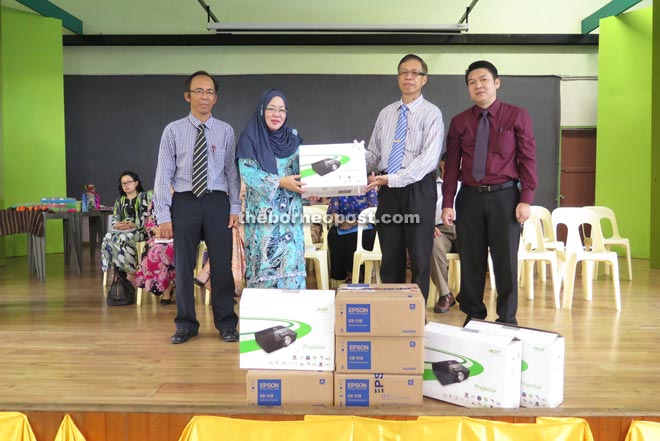 Chan (second right) presents the LCD projectors to Saftuyah, as PTA Batu Lintang treasurer Uden Sanggai (left) and secretary Sanada Jaki (right) look on.