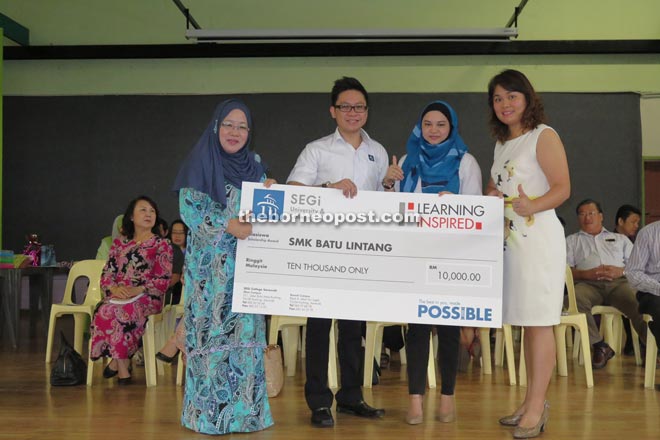 Lau (right) handing over a mock cheque for RM10,000 to Saftuyah (left) witnessed by the staff of the college.