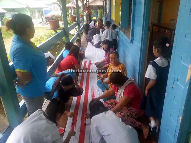 Parents, teachers, pupils and the local community creating the 30 metre long flag. 