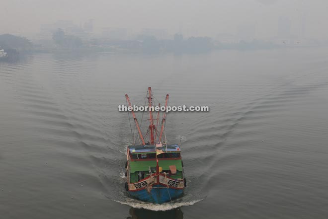A fishing boat is seen travelling down the Sarawak River amidst the hazy surroundings.