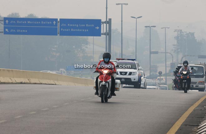 Motorcyclists wearing facemasks as they travel along Pending Road in Kuching. — Photo by Kong Jun Liung