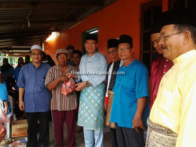 Julaihi (third left) distributes the sacrificial meat to a local Muslim while others look on. 