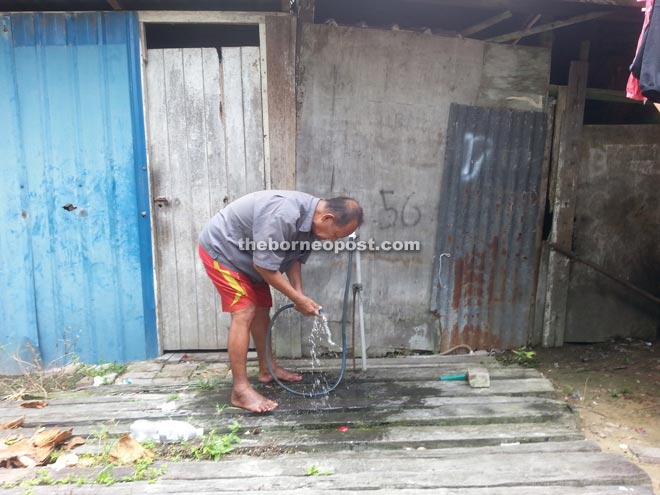 George washes his hands in front of his hut. (Inset) George is seen in clothes he has worn for the past week.