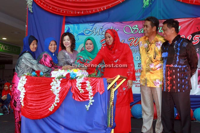 Rubiah (centre) cuts a cake to launch the Samarahan District Level Woman Day 2015 celebration witnessed by the event organising committee.