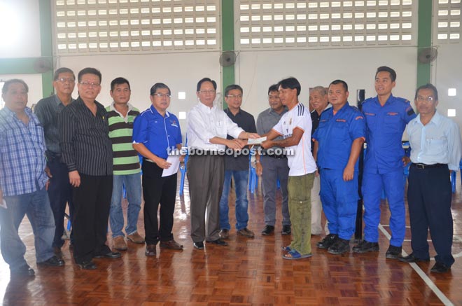 Lau (sixth from left) presents the assistance to a fire victim. Dr Annuar is on Lau’s left.   