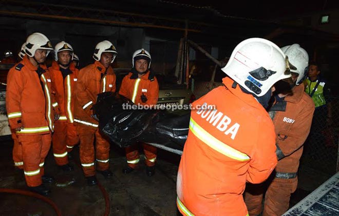 Fire-fighters carrying the charred remains of one of the victims.