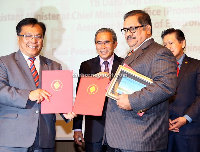 Mohamad Kadim (left) exchanges the MoA with Shakor as Len Talif (centre) looks on. — Photos by Muhammad Rais Sanusi