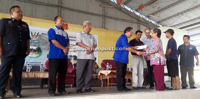 Sagah (left) presenting flood relief welfare aid to one of the recipients.