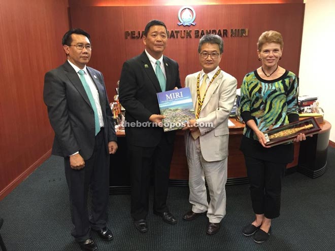 Lai (second left) presents a book on Miri to Yun and a souvenir to Melanie (right) during their courtesy call.