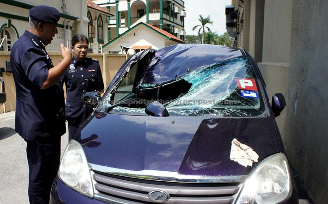 Shaikh Abdul Adzis Shaikh (left) inspecting the student’s car at the site of the incident. — Bernama photo