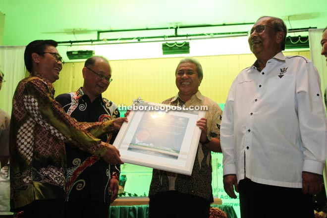 A recipient receives an indigenous communal reserve title from Adenan (second left), while (from left) Awang Tengah and Yussibnosh look on.