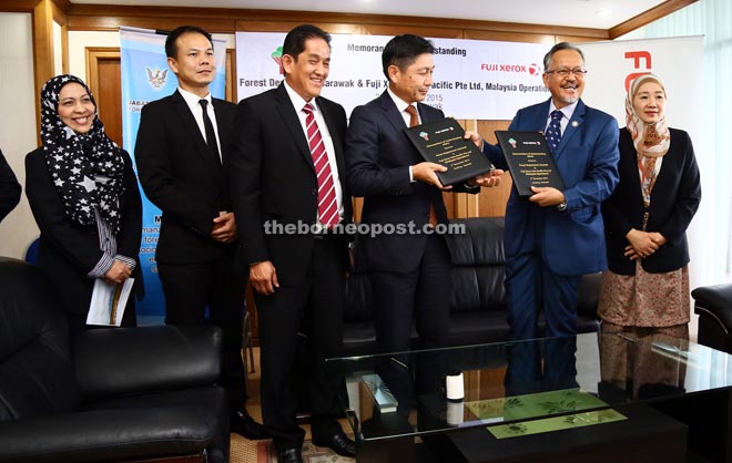 Sapuan (second right) and Toru (third right) exchanging the MoU which was witnessed by Latifah (right) and Loy (third left). Also with them are Fuji Xerox Asia Pacific Pte Ltd (Malaysia Operations) Quality Management manager Sharifah Suhaila Syed Musa (left) and Fuji Xerox Asia Pacific Pte Ltd (Malaysia Operations) Sarawak branch manager Edward Lim (second left). - — Photo by Muhammad Rais Sanusi