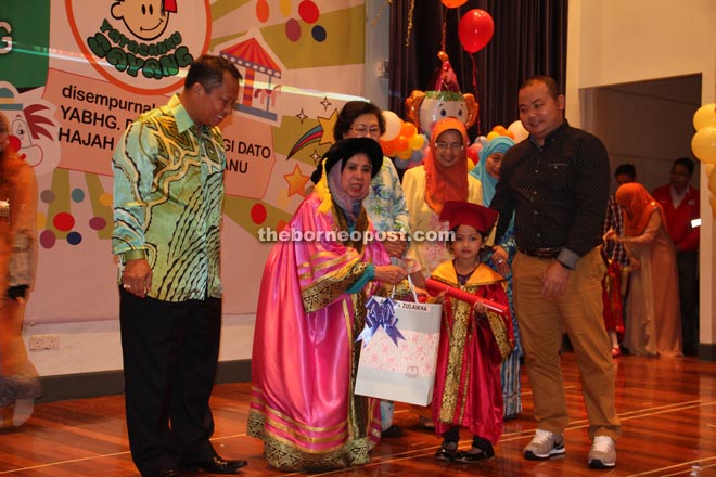 Rosey (second left) presents a scroll to one of the pupils as others look on. 