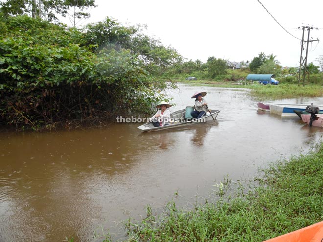 Residents use boats to commute as the road leading to their longhouses is inundated.