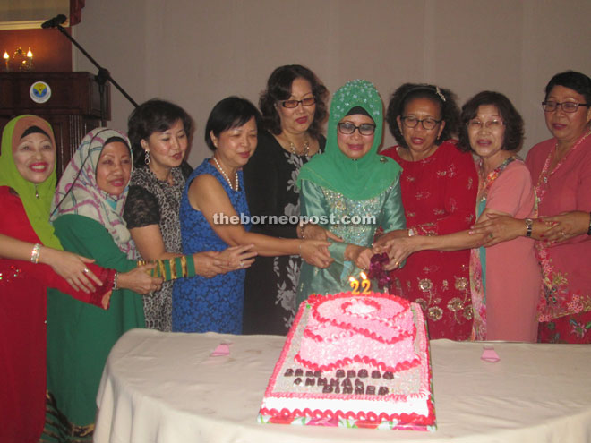 Fatimah (sixth left) joining Yong (fifth left) and the group members in cutting a cake to mark their 22nd anniversary. 