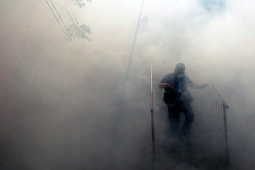 AFP | A photographer walks through the fumes as Health Ministry employee fumigate against the Aedes aegypti mosquito to prevent the spread of the Zika virus in Soyapango, six km east of San Salvador, on January 21, 2016