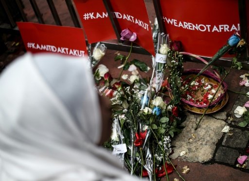 A woman offers flowers during a vigil outside the damaged Starbucks coffee shop in Jakarta on January 15, 2016, a day after a series of explosions hit the Indonesian capital. -AFP Photo