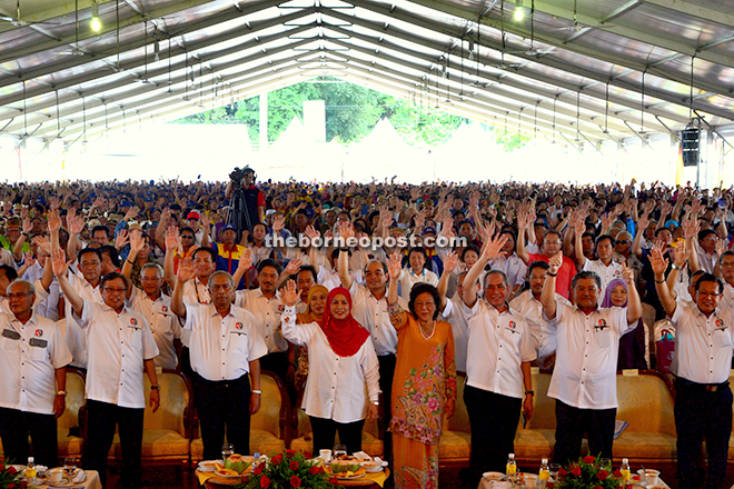Adenan, Jamilah (front, third and fourth left, respectively) and others raise their hands during a segment of the opening ceremony. 