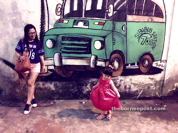 Amanda and her niece enjoy their time at the site of the nostalgic green-and-white bus wall painting at Blacksmith Road.